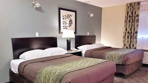 A hotel room with two beds, a nightstand, a lamp, a framed artwork on the wall, and a patterned carpet. - Lacombe Motor Inn (Lacombe)