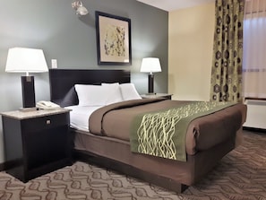 A hotel room with a large bed, two bedside tables with lamps, a telephone, and a framed artwork on the wall. - Lacombe Motor Inn (Lacombe)