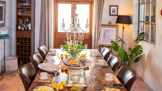 Comedor con una mesa de madera dispuesta para una comida, rodeado de sillas de cuero.