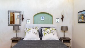 Un dormitorio con una cama, dos mesitas de noche, un espejo y cuadros en la pared.