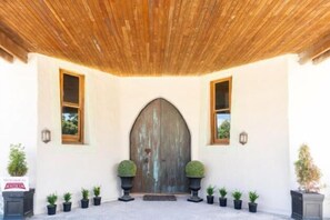 A building entrance with a wooden door, potted plants, and a tiled floor. - Antria Boutique Lodge (Blenheim)