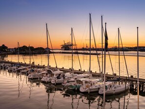 Un puerto deportivo con varias embarcaciones amarradas a muelles de madera durante el atardecer.