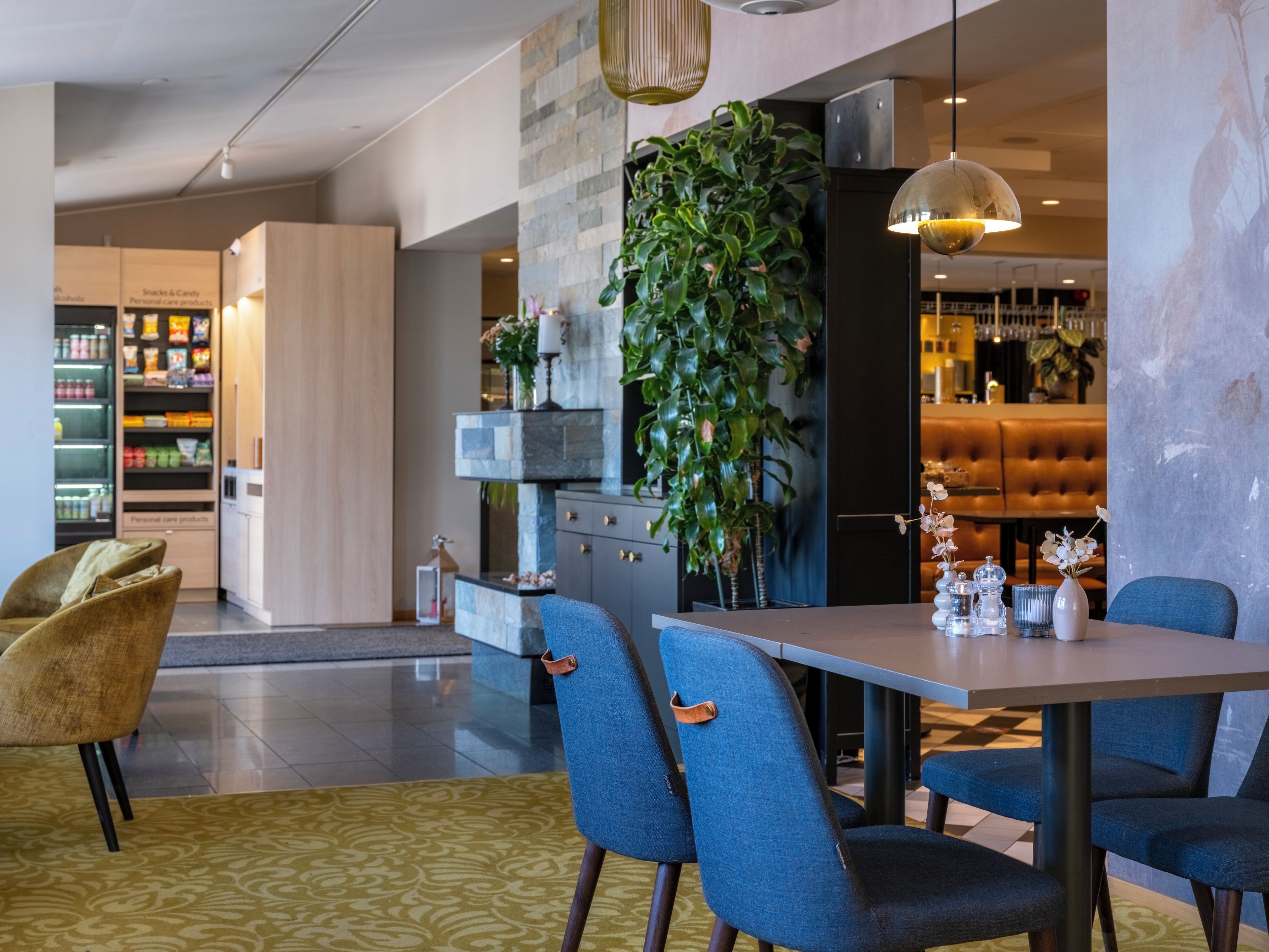 Een modern interieur met een eethoek, een keuken en een zithoek met een grote plant.