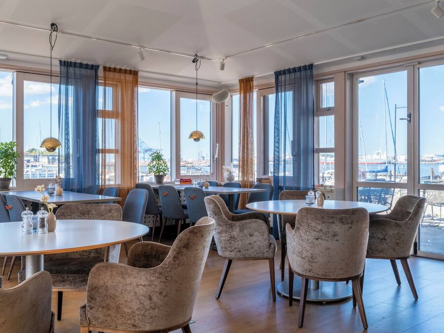 Un restaurante con amplios ventanales, varias mesas y sillas.