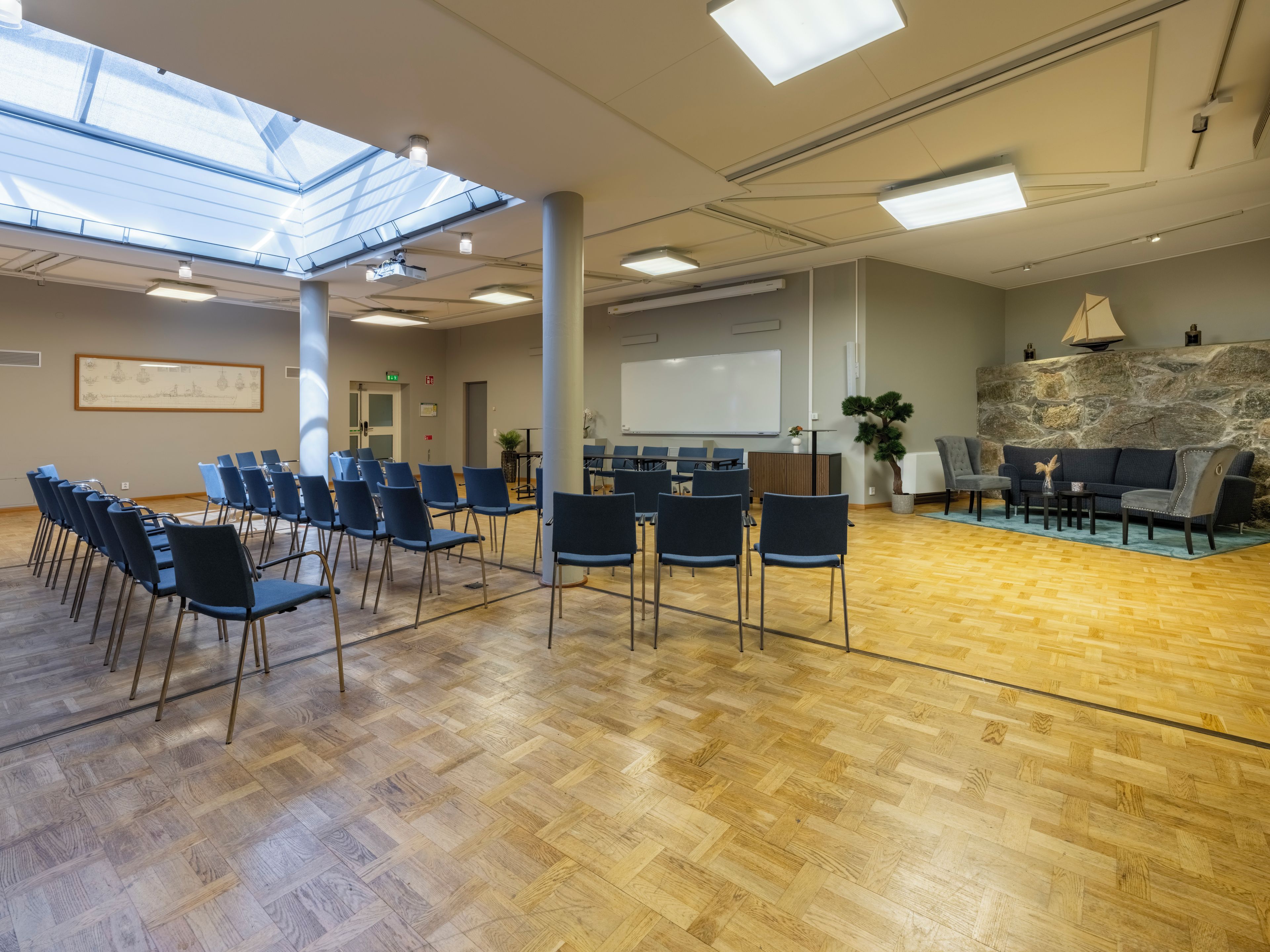 Un salón de conferencias con techo alto, tragaluces y una pizarra.