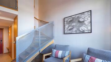 A modern interior with a staircase, a sofa set, and a framed artwork.