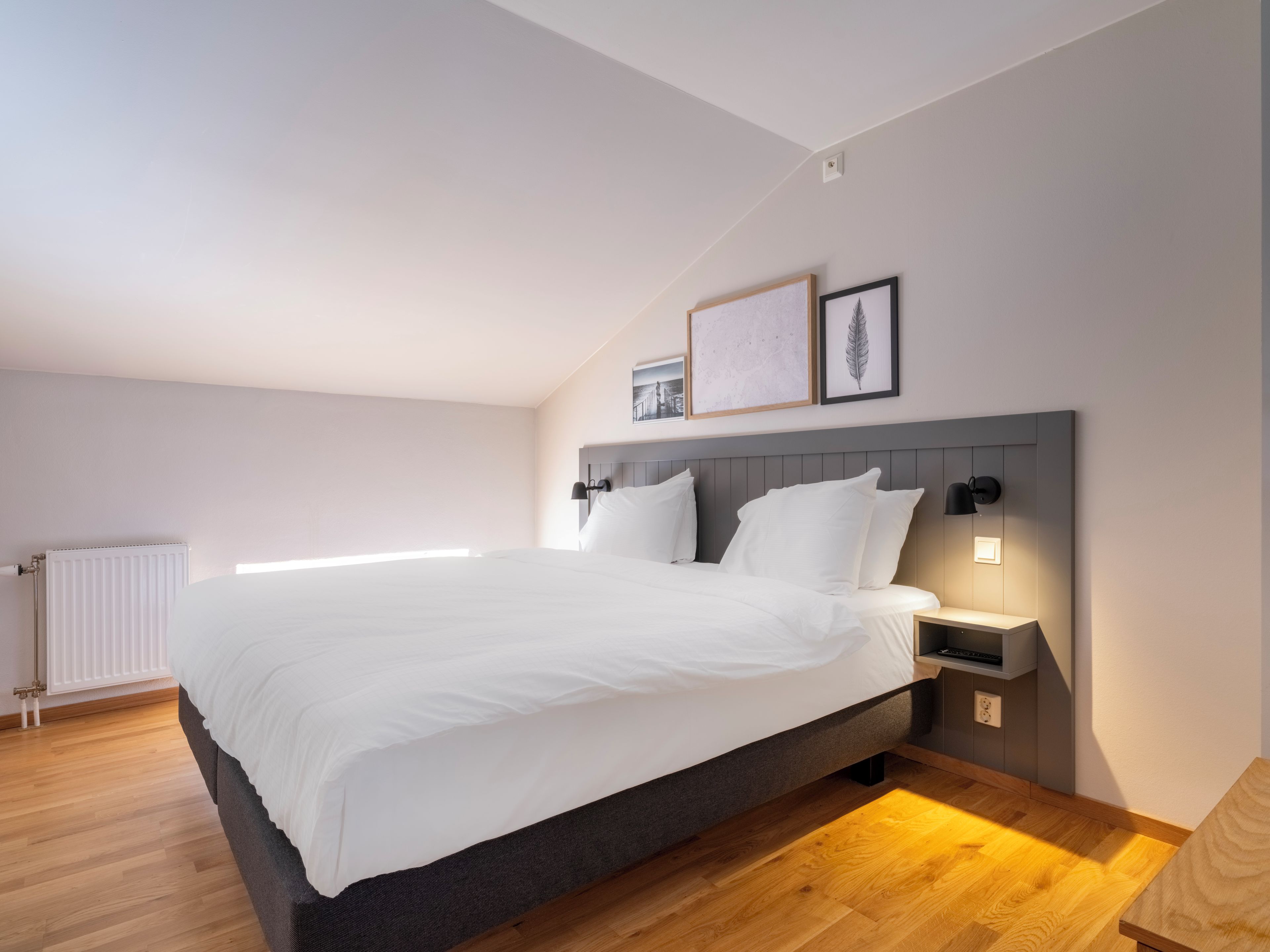 Ein modernes Schlafzimmer mit einem großen Bett, Nachttischen und einer Heizung.