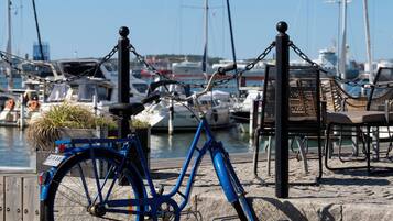 A blue bicycle parked at a dock with boats in the background.