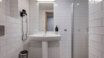 Een moderne badkamer met witte metrotegels, een wastafel op voet, een glazen douchecabine en een toilet.