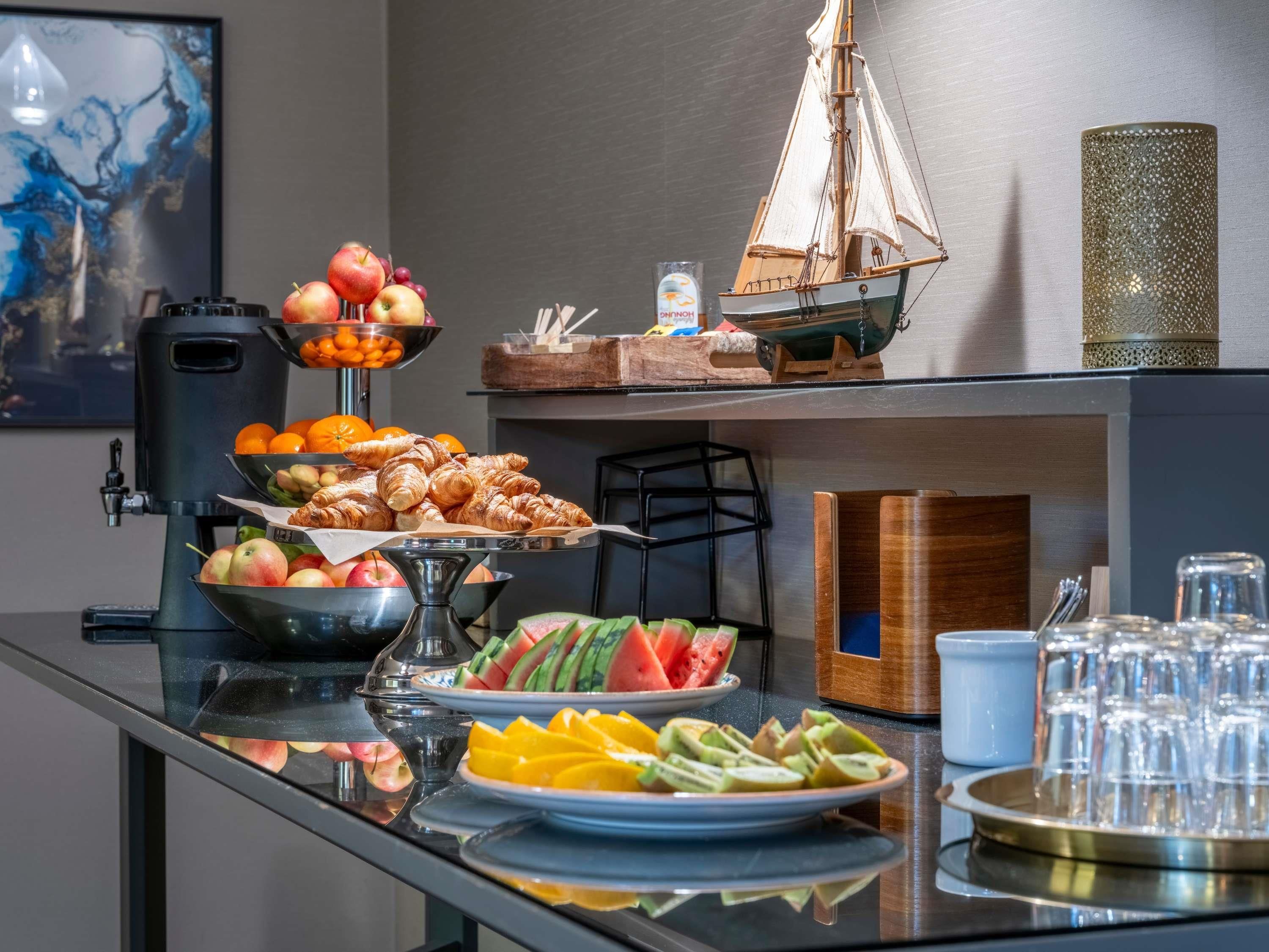 Ett buffébord med olika sorters mat, inklusive frukt, bakverk och en modell av ett fartyg.