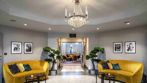 A spacious lobby with two yellow sofas, a chandelier, framed pictures on the walls, and a dining area in the background. - Mercure Gothenburg (Vastra Frolunda)