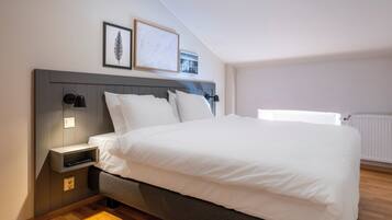 Un dormitorio moderno con una cama grande, una mesita de noche, una lámpara de pared y un cuadro enmarcado.