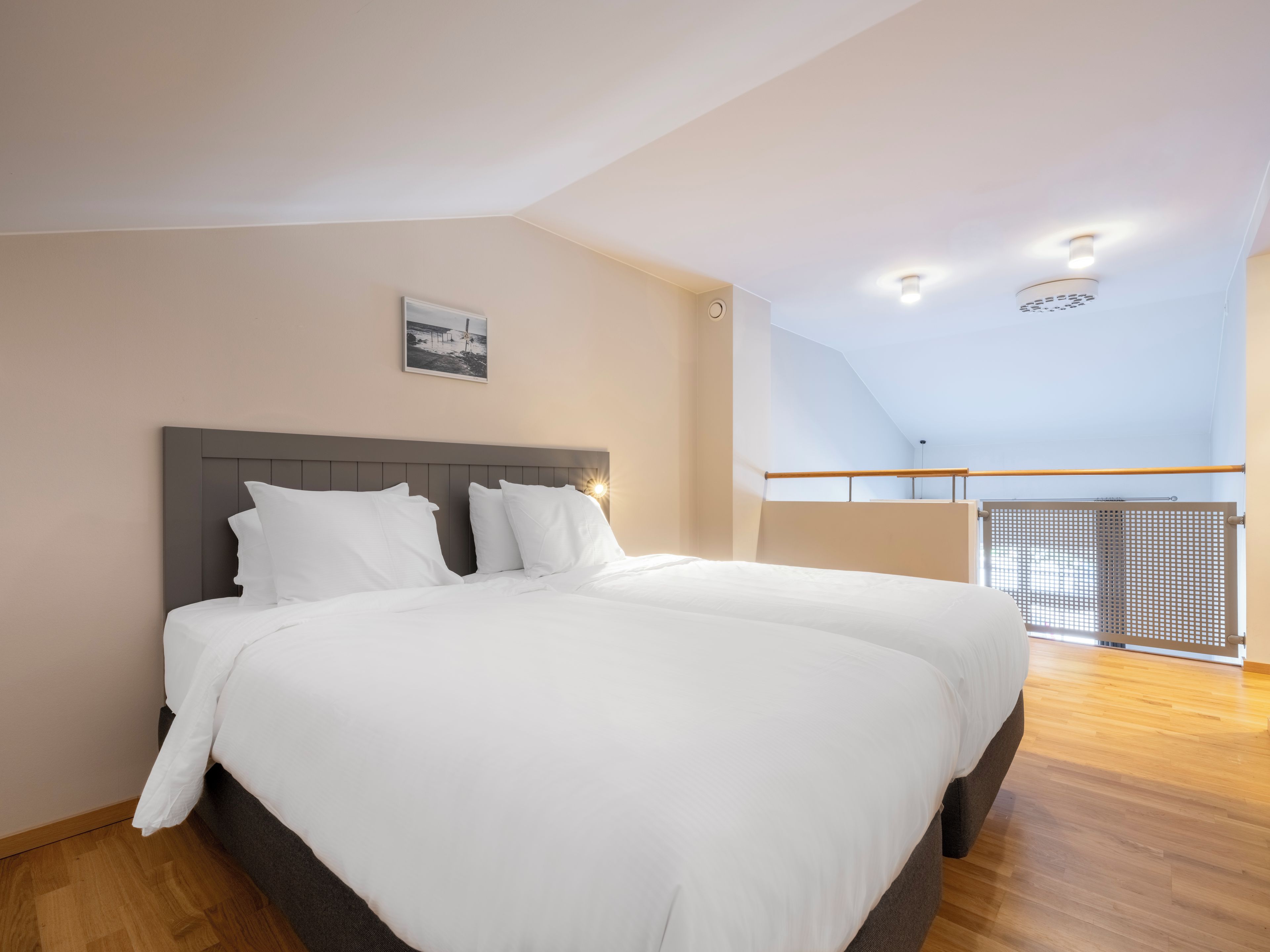 A bedroom with a large bed, a headboard, and a view of a balcony.