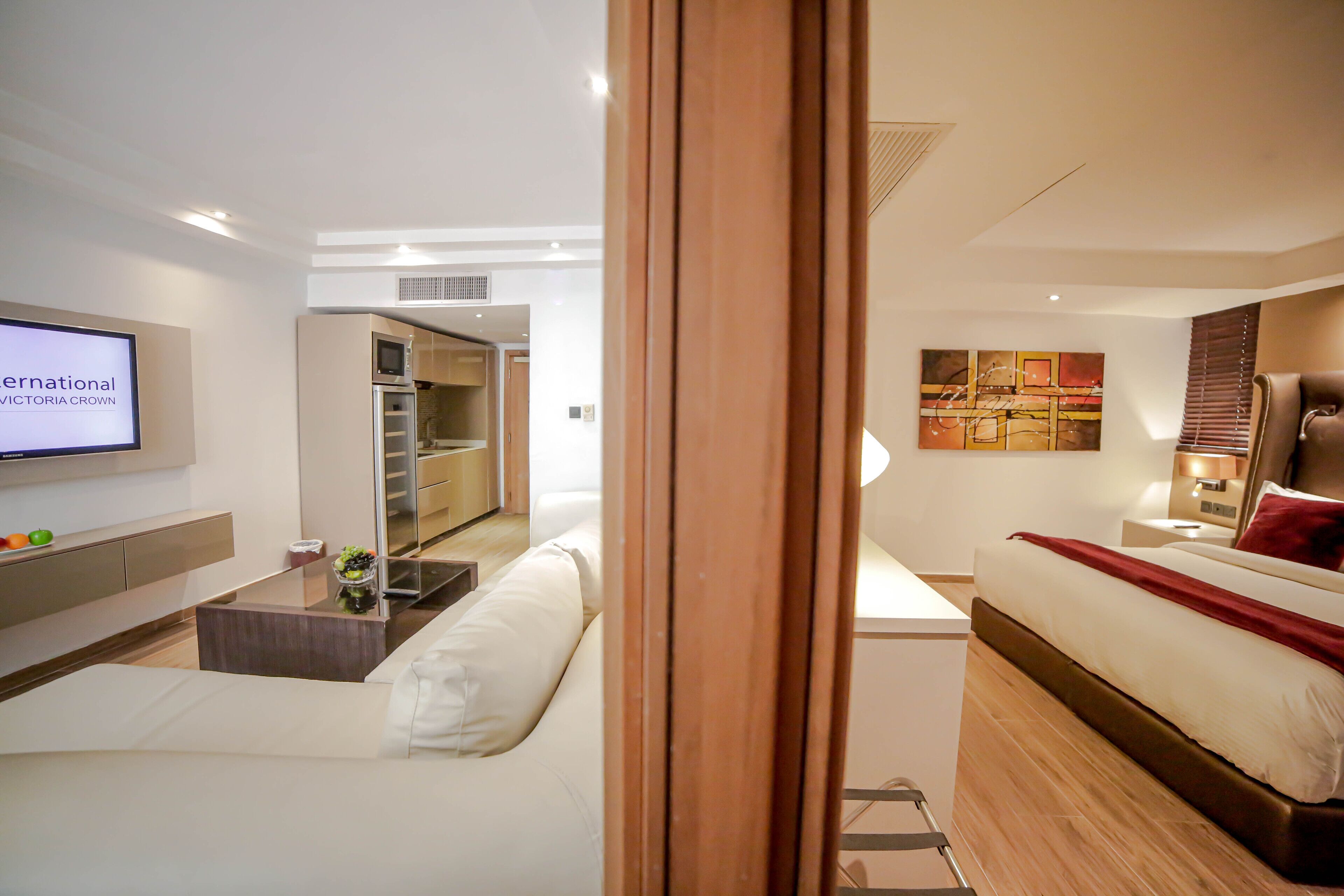 A modern hotel room with a bed, a TV, a sofa, a coffee table, and a view of the bathroom.