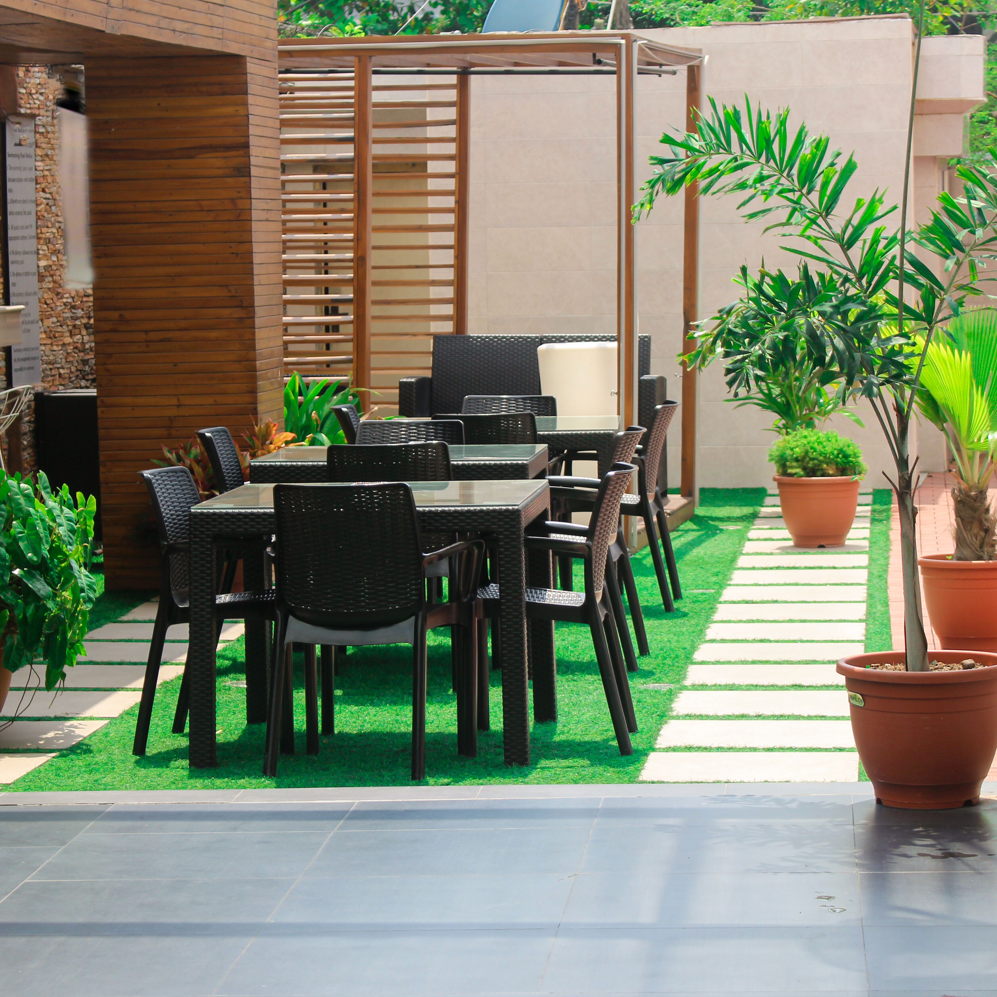 An outdoor patio area with a table and chairs, surrounded by potted plants and a wooden fence.