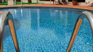 A swimming pool with a metal ladder, lounge chairs, and potted plants. - Victoria Crown Plaza Hotel (Lagos)