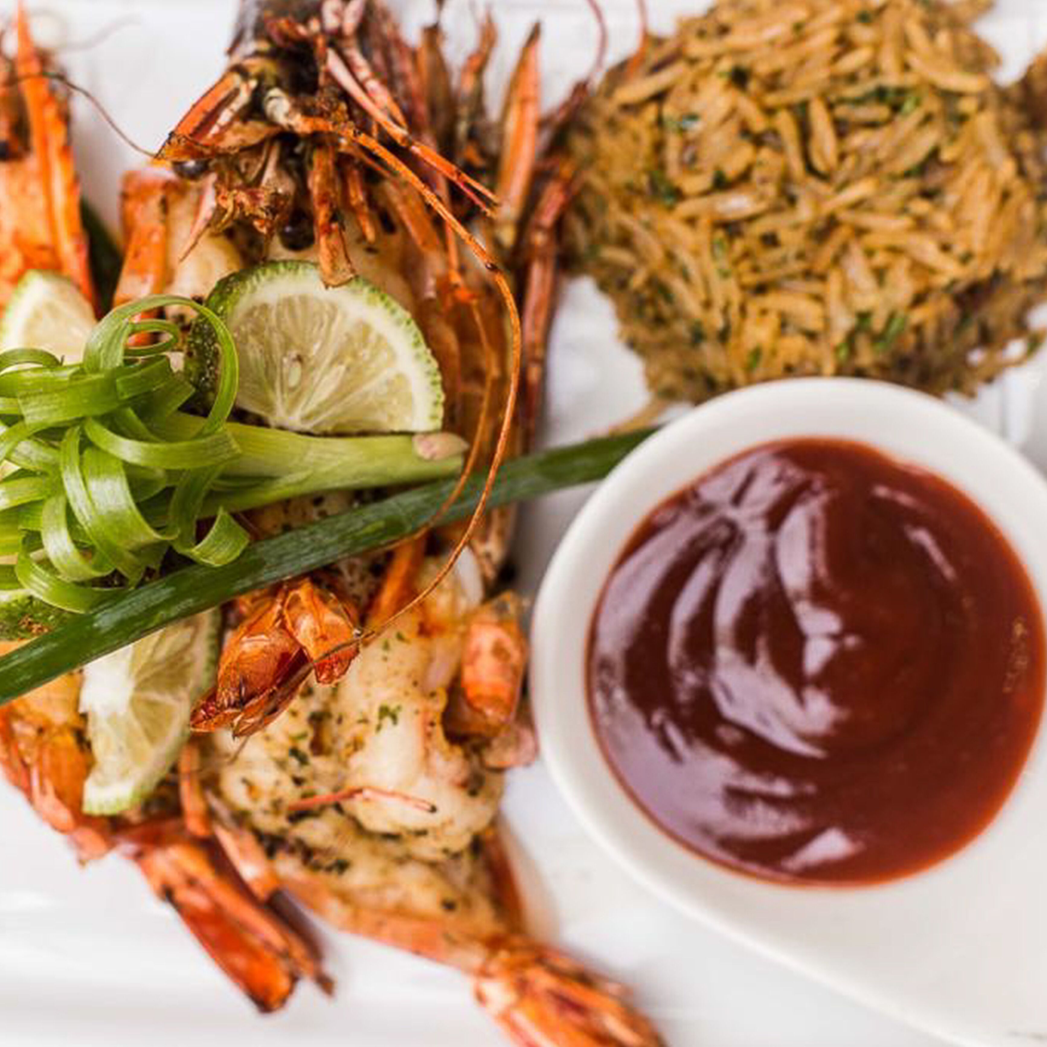 Een bord gekookte kreeft met rijst en een schaaltje saus.