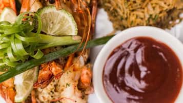 A plate of cooked lobster with a side of rice and a bowl of sauce.