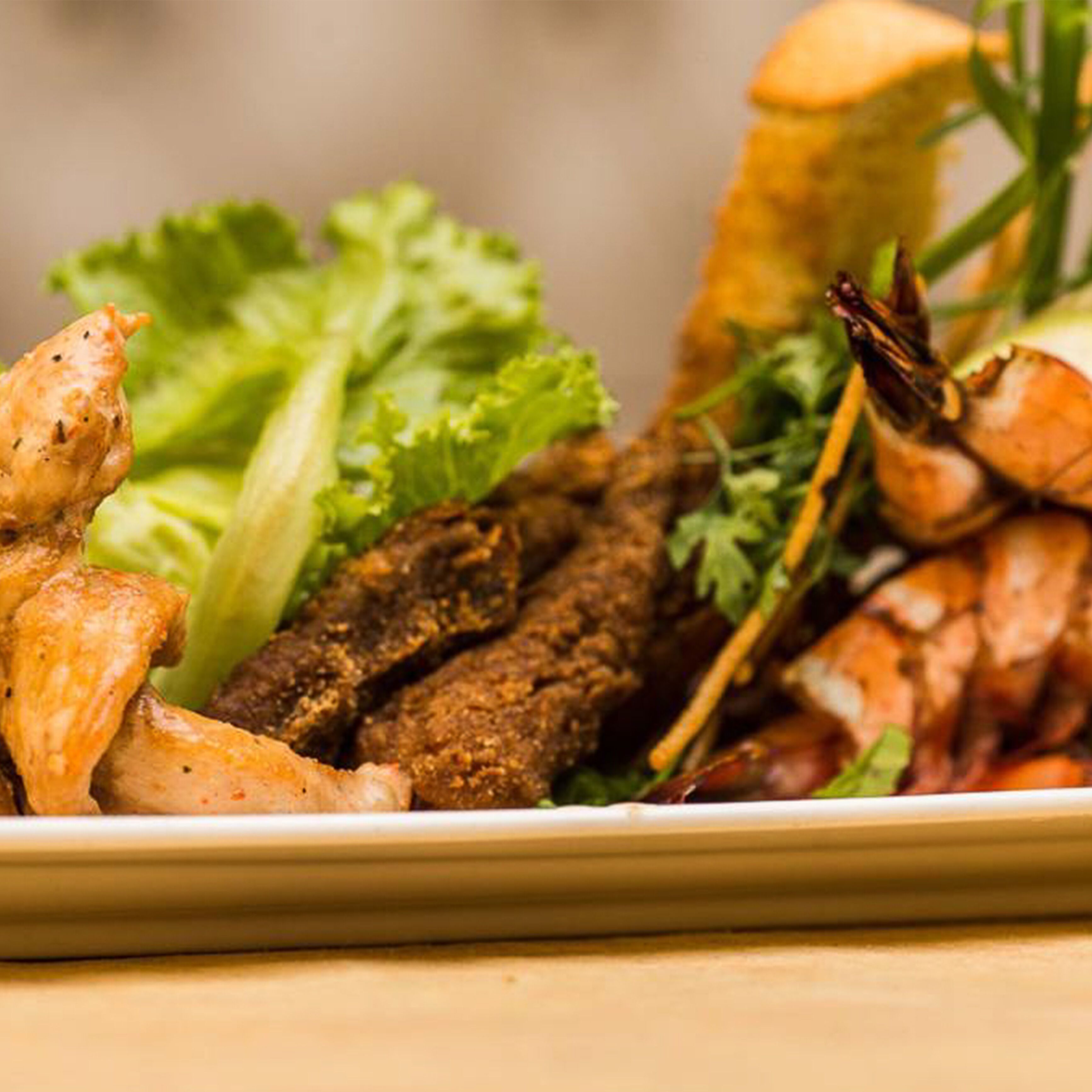 A plate of food including shrimp, meat, and vegetables.