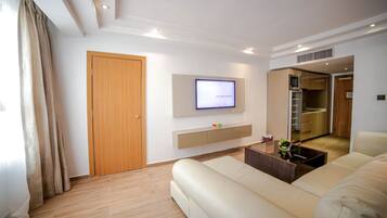 A modern living room with a flat-screen TV, a sofa, a coffee table, and a wooden door.