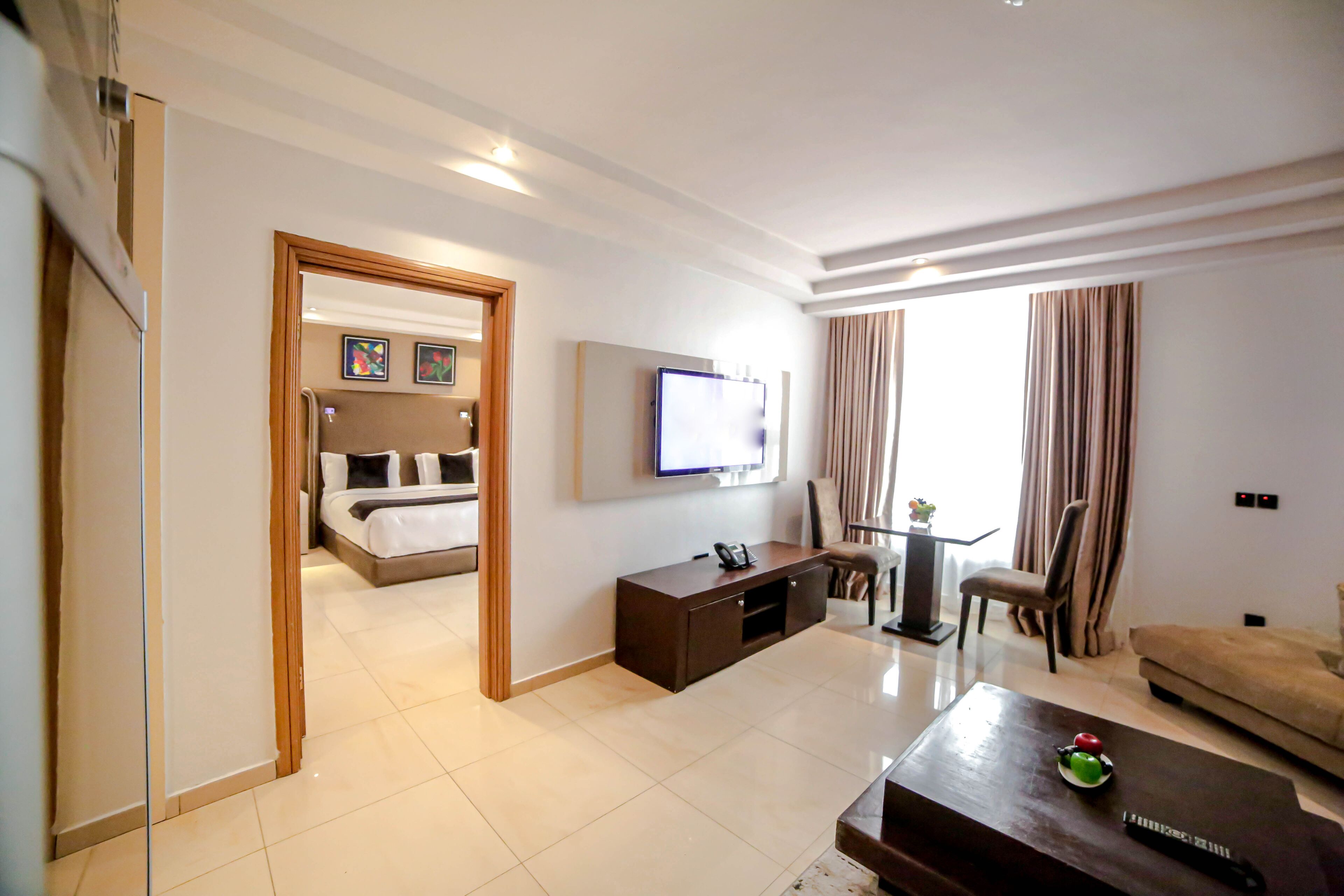 A modern hotel room with a bed, a TV, a desk, and a sofa.