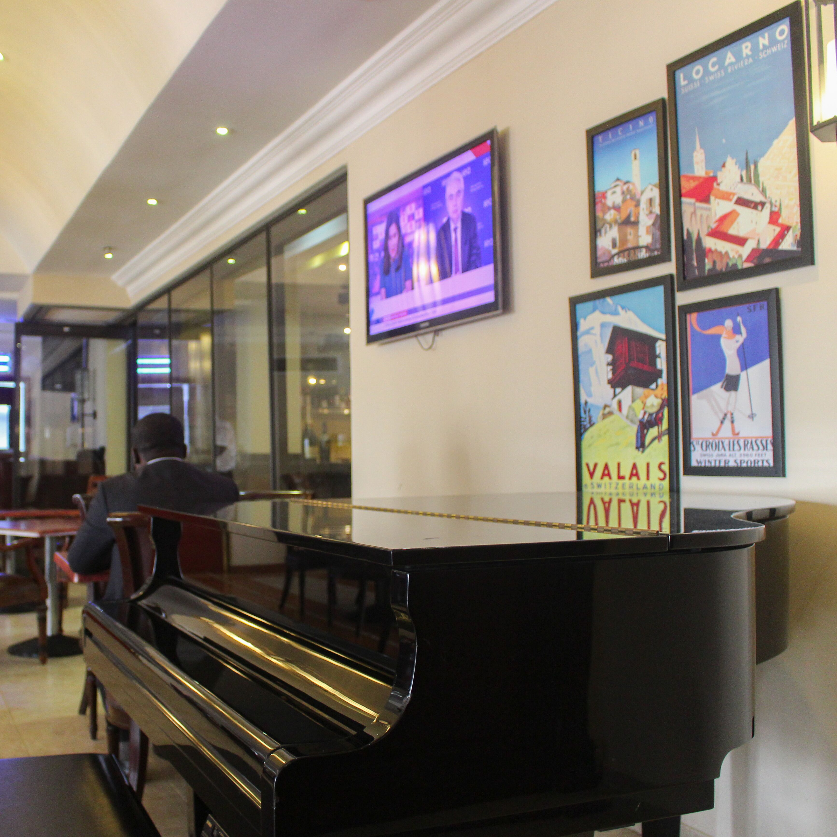 Un hall d’entrée agrémenté d’un grand piano, d’un écran de télévision et de posters encadrés accrochés au mur.