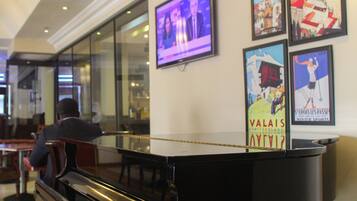 Un hall d’entrée agrémenté d’un grand piano, d’un écran de télévision et de posters encadrés accrochés au mur.