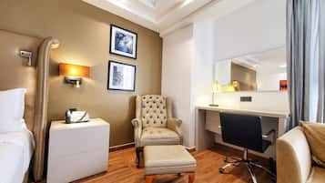 Une chambre d’hôtel comprenant un lit, un bureau, une chaise, une petite table, un téléphone et une lampe fixée au mur.