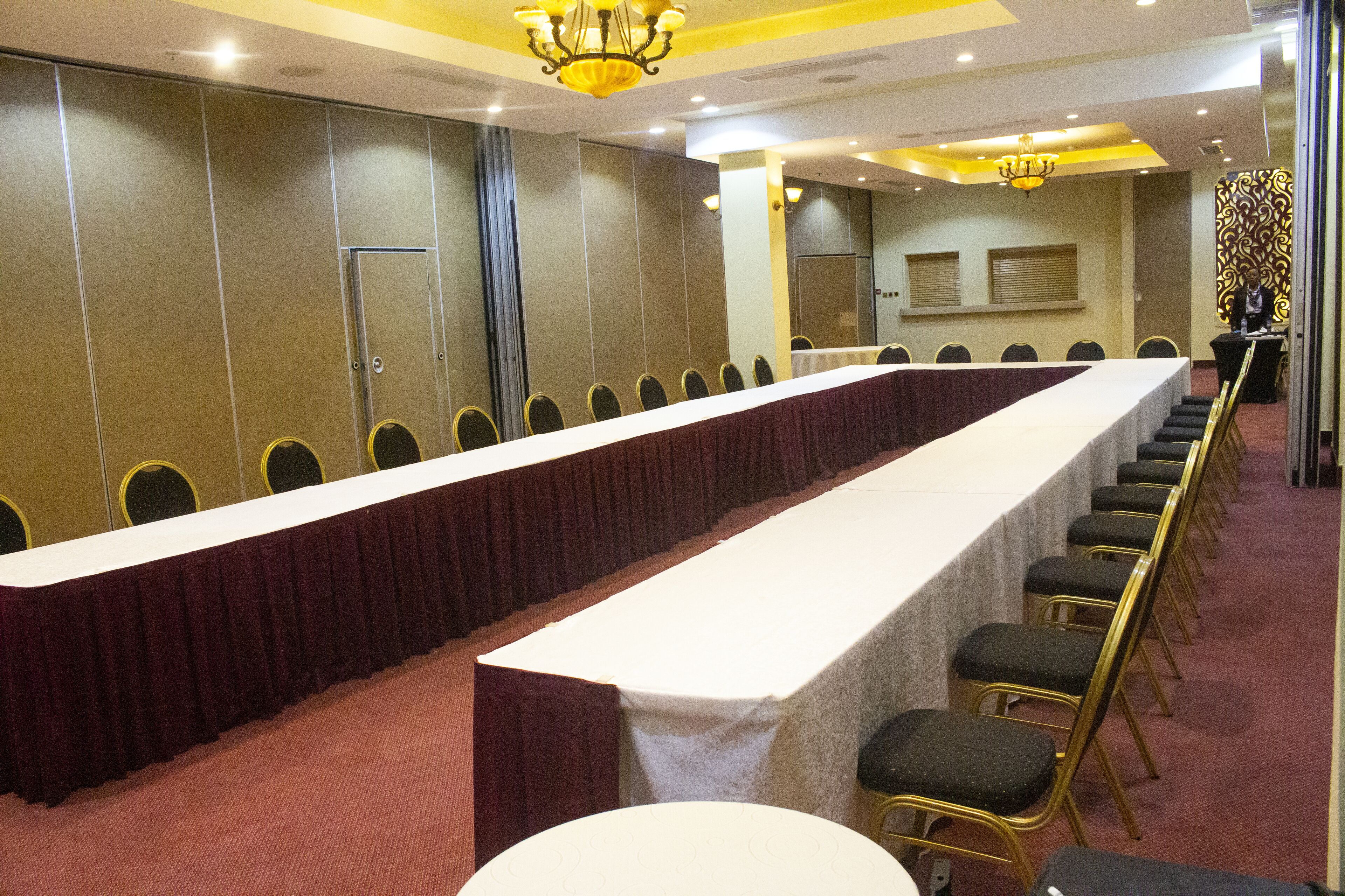 A conference room with a long table, rows of chairs, and a chandelier.