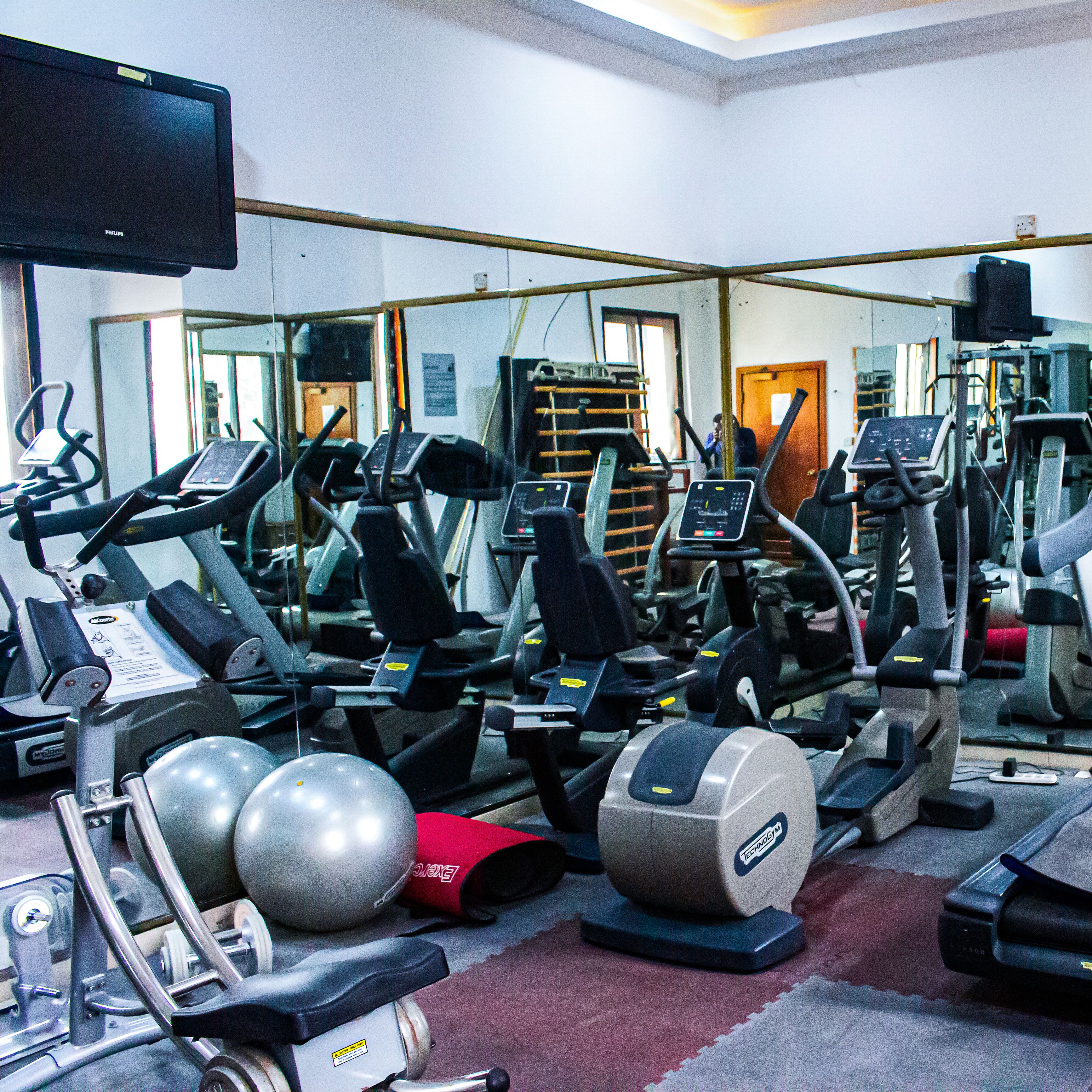 A gym with various exercise equipment, including treadmills, elliptical machines, and weights.