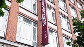 A maroon sign with white lettering for "INDUSTRIAL PARKS HOSTEL" on a brick building.