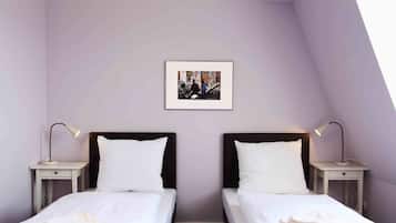Habitación doble con dos camas, ropa de cama blanca y una foto enmarcada en la pared.