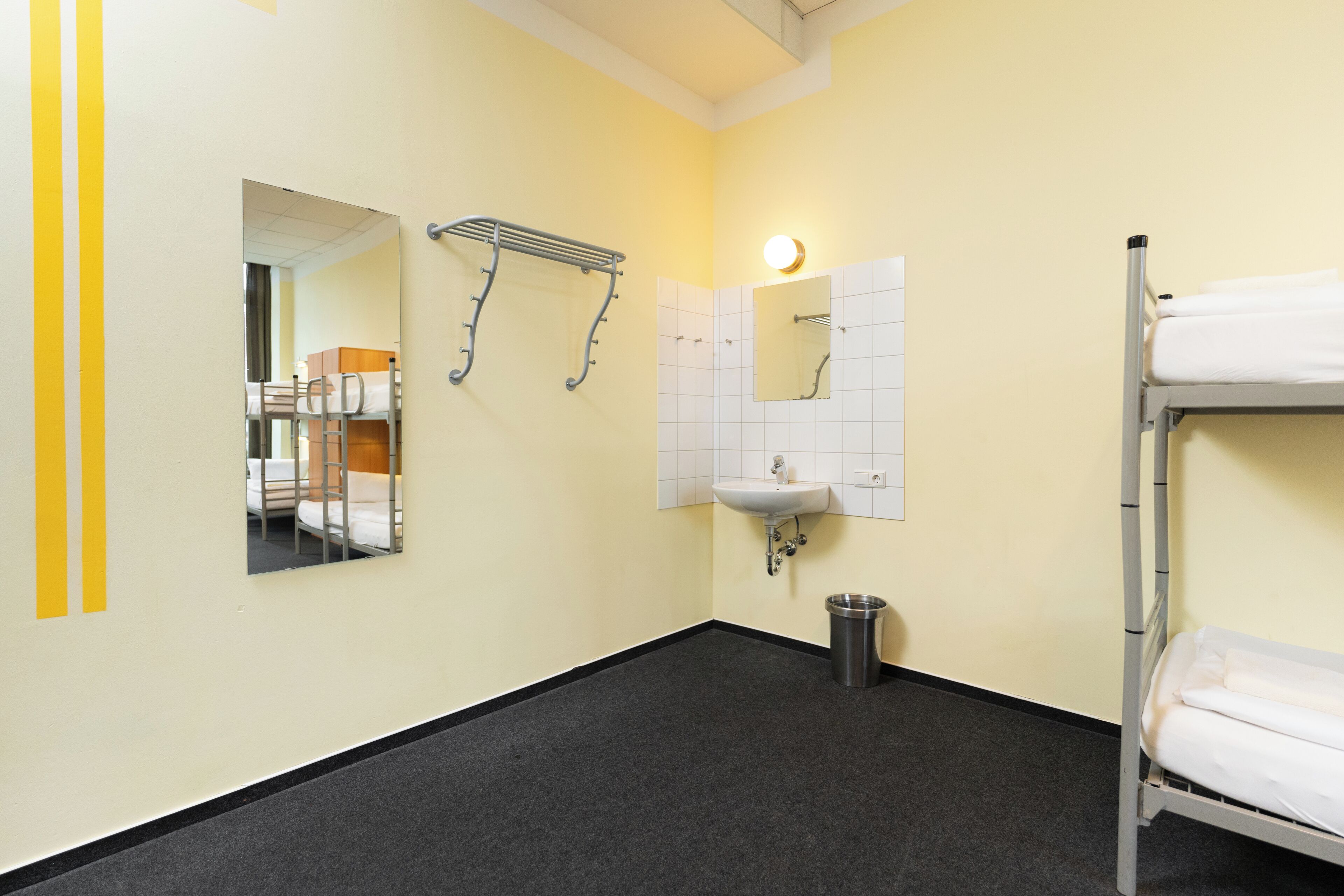 A small, clean bathroom with a bunk bed, a sink, and a mirror.