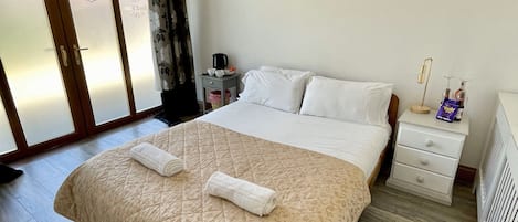 A hotel room with a large bed, a bedside table with a lamp, a wall-mounted artwork, and a sliding glass door.