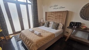 A hotel room with a large bed, a headboard with a motivational quote, a coffee station, and a view through the glass doors. - The Old Mill Rooms (Yarm)