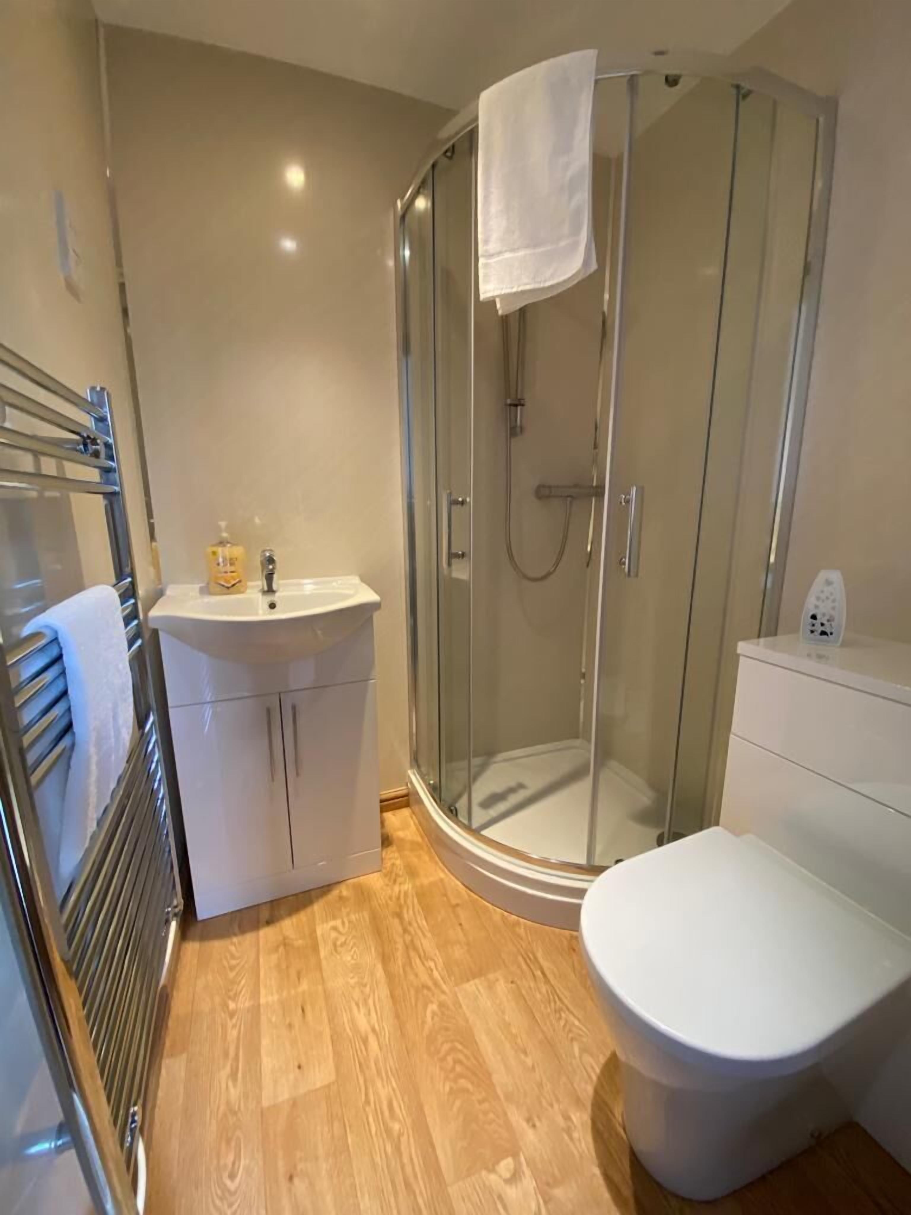 A modern bathroom with a glass-enclosed shower, a white sink, and a toilet.