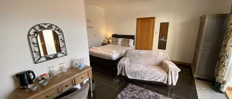 A bedroom with a bed, bedside table, chair, and a large mirror on the wall.