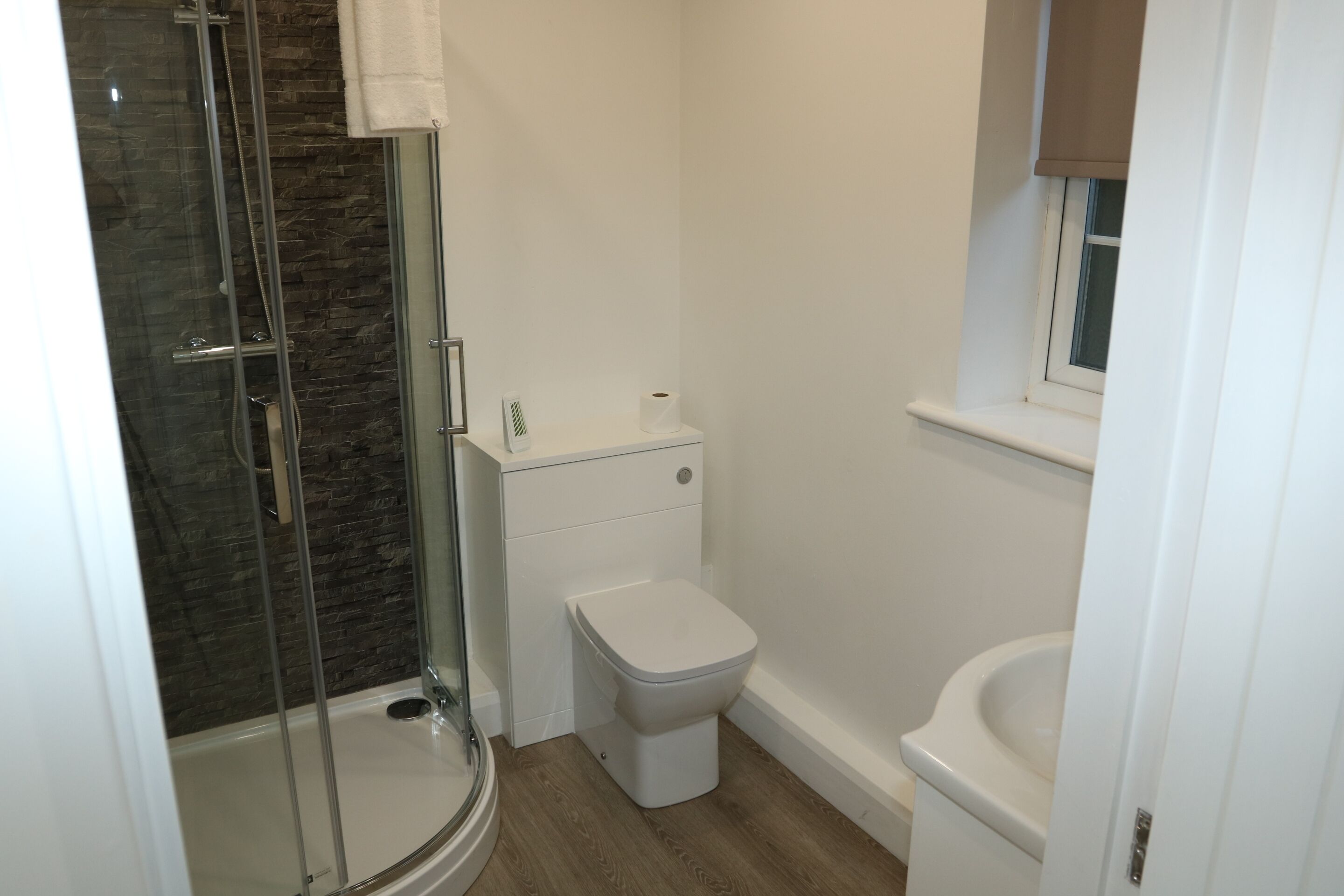 A bathroom with a glass-enclosed shower, a toilet, and a sink.