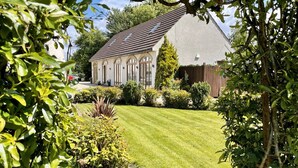 A well-maintained lawn, a traditional house with a sloped roof, and a wooden fence in the background. - The Old Mill Rooms (Yarm)