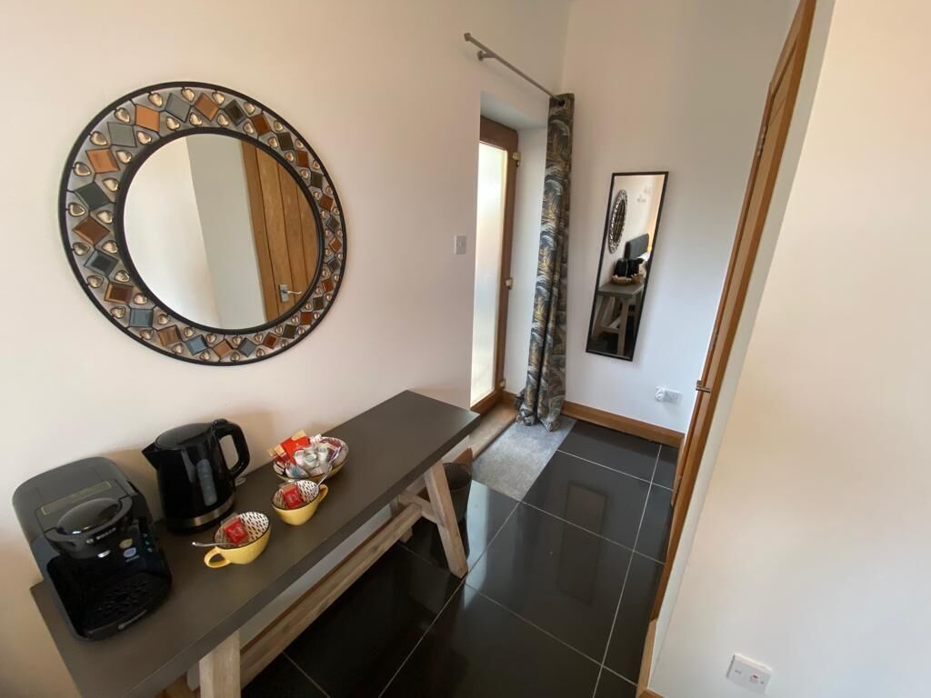 Ein modernes Badezimmer mit einem runden Spiegel, einer Kaffeemaschine und einem kleinen Tisch mit Tassen.