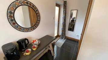 A modern bathroom with a round mirror, a coffee maker, and a small table with cups.