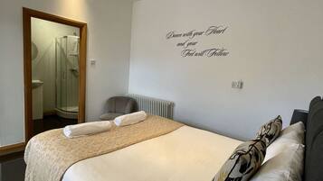 A hotel room with a large bed, a mirror, a shower, and a wall with a motivational quote.