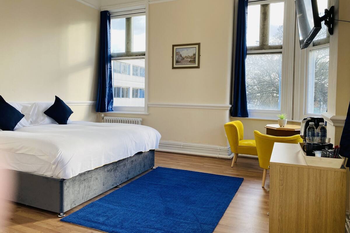 Una habitación de hotel con una cama grande, un escritorio, una silla y un televisor.