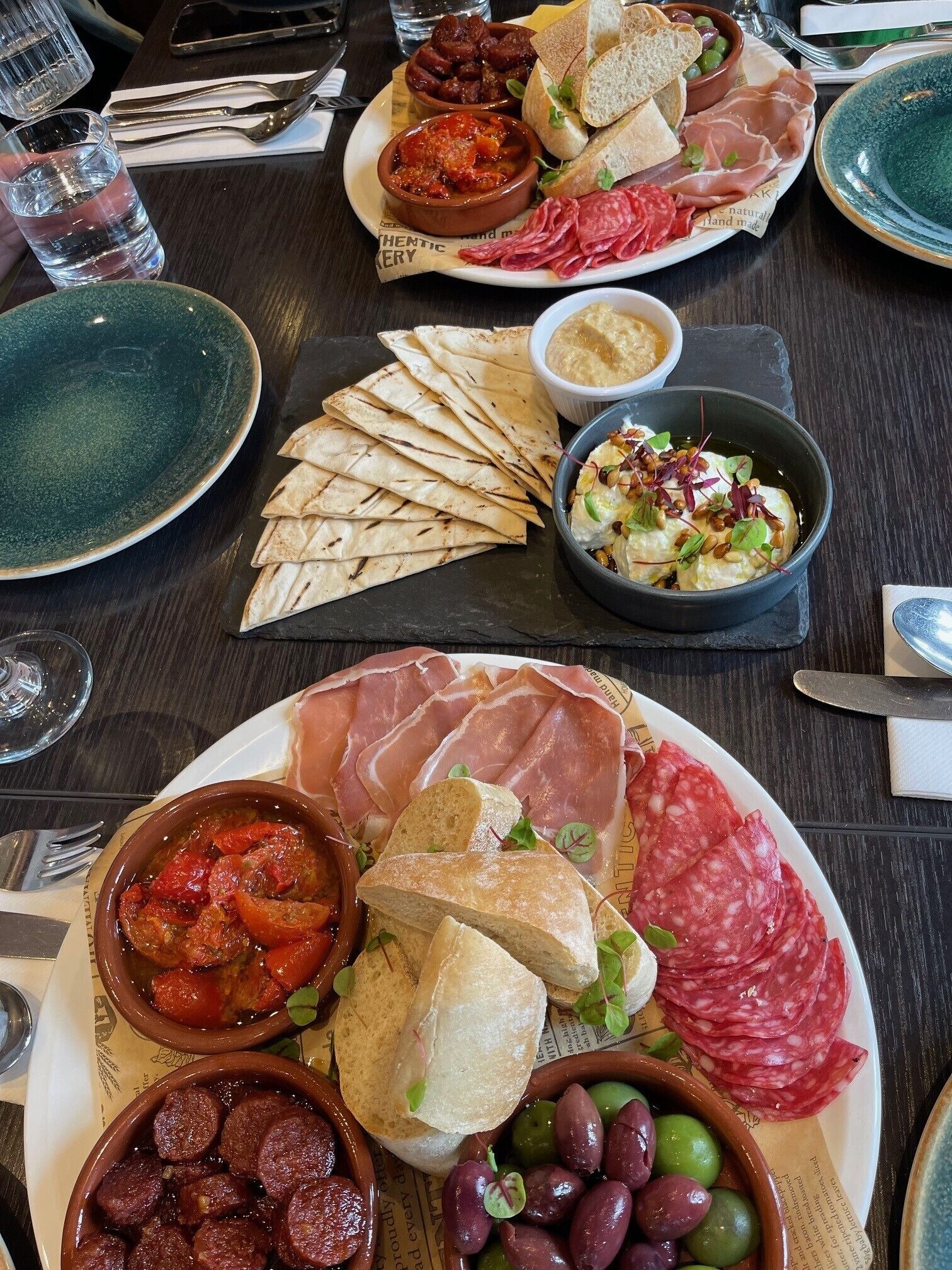 A table set with various food items including bread, olives, and charcuterie.