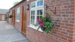 A brick building with white-framed windows, a door, and hanging flower baskets. - The Royal Oak - Inn (Loughborough)