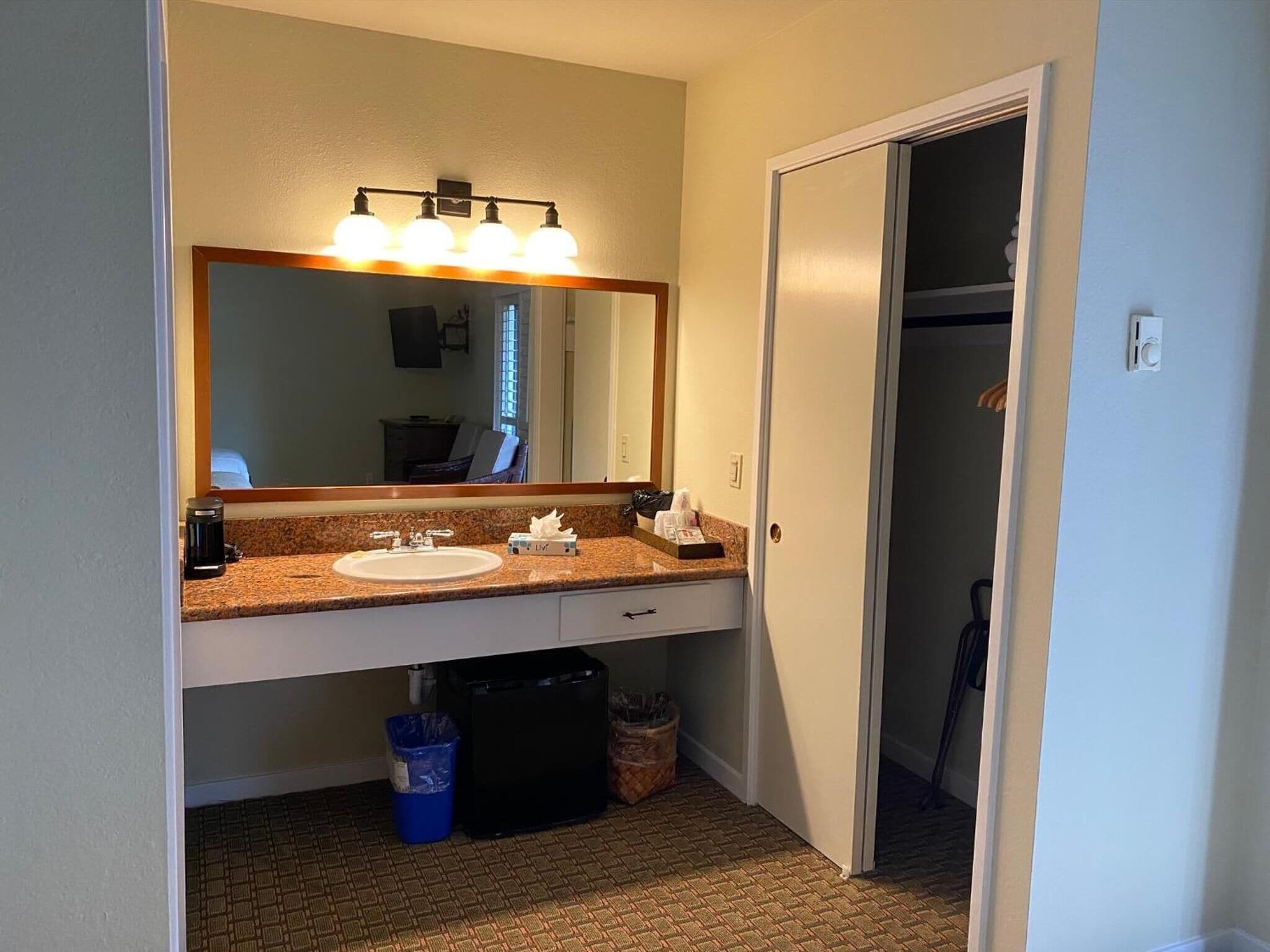 A hotel bathroom with a sink, mirror, and vanity.
