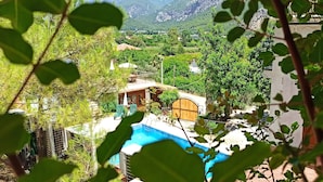 Vista de una piscina rodeada de vegetación y edificios, con montañas al fondo.