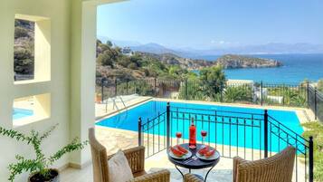Ein Balkon mit Blick auf einen Pool und das Meer.