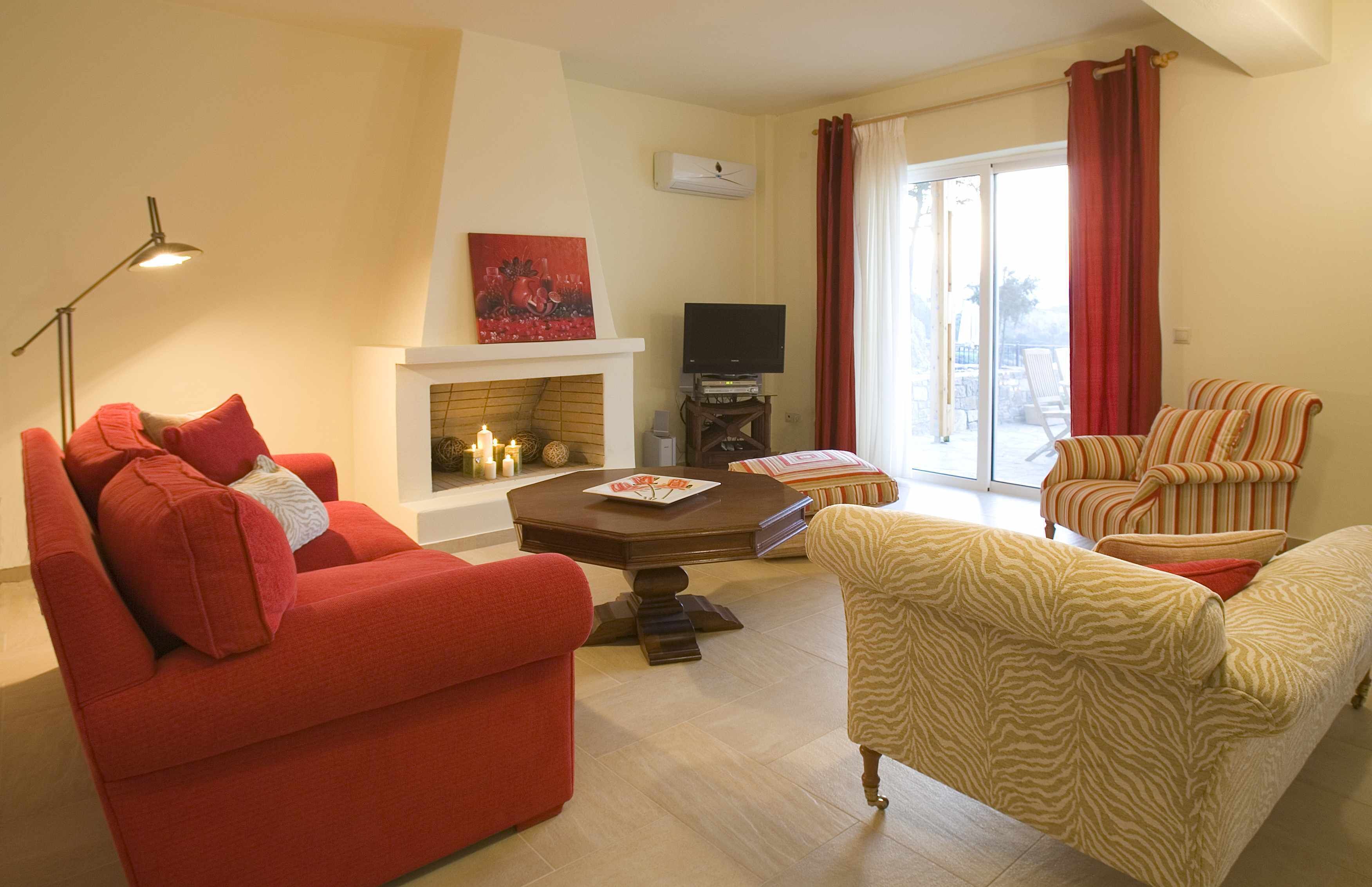 Una sala de estar con chimenea, televisor y sillones a rayas.