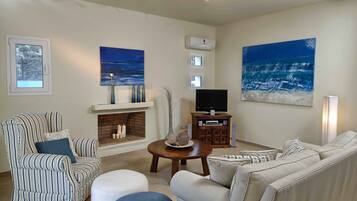 A living room with a fireplace, striped armchairs, a sofa, a coffee table, and artwork on the walls.